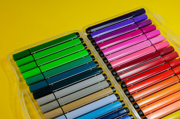 Large set of colorful felt-tip pens for drawing on a colored background.