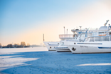 Passenger ships in dock on frozen river. Boats on ice