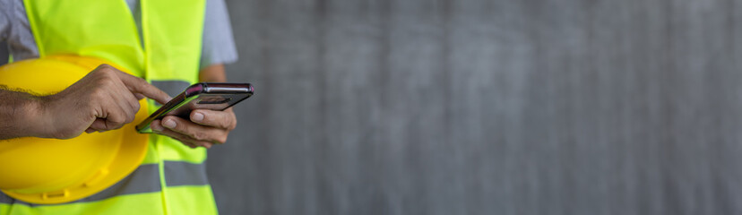 construction worker hands touch screen using smartphone on cement wall background with copy space