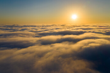 Wall Mural - striking aerial view of the sunset sky with the clouds below us. the shadows projected from the sun 