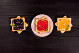 Fototapeta Zwierzęta - Delicious toasts with various sweet jams on black background. Copyspace for your text, banner.