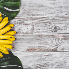 Wall Mural - Raw Organic Yellow Baby Bananas in a Bunch on white wooden background top view. Copyspace for your text, banner.