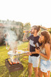 © Impact Photography - Friends drinking beer and grilling meat at backyard barbecue party