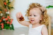 © Elena  - A little girl examines a pine cone. Close-up game. A pretty young blonde is studying in a Montessori style class or a home concept. Explores natural materials.