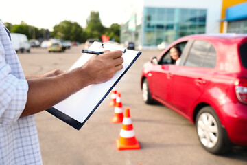 instructor with clipboard near car outdoors, closeup. driving school exam