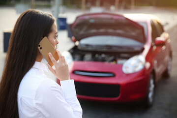 Wall Mural - Stressed woman talking on phone near broken car outdoors