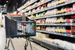 © LIGHTFIELD STUDIOS - Shopping cart near packages on shelves in supermarket