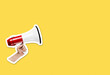 Hand holding megaphone on bright yellow background with plenty of copy space. Magazine collage cut out style
