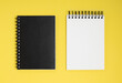 Two notepads on a yellow background. Overhead view of open and closed notepads with copy space.