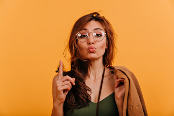 Canvas Print - Funny attractive girl sends kiss to camera. Portrait of cute positive lady in autumn clothes on orange background