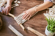 Female hands working a macrame decoration on a wooden desk