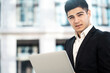 © muse studio - a dark-haired businessman of European appearance stands in a business center in a stylish black suit. holds a laptop computer in his hands. copy space. banner for the site.