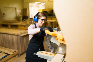 Wall Mural - Female worker using a bench saw and wearing protective equipment