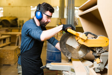 Sticker - Side view of an hispanic man using a saw with protective equipment