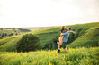 © Alexander - young beautiful couple red-haired girl in a pink dress and green jacket a man in a gray t-shirt and green shorts are having fun in the grass in a field in nature at sunset