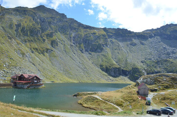 Sticker - Beautiful shot of two houses and three cars near the river in a mountainous area