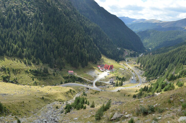 Wall Mural - Mesmerizing shot of mountainous forests with houses and bumpy roads under the cloudy sky