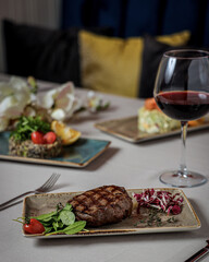 Poster - Vertical shot of asteak with vegetables on a beautiful ceramic plate and a glass of red wine