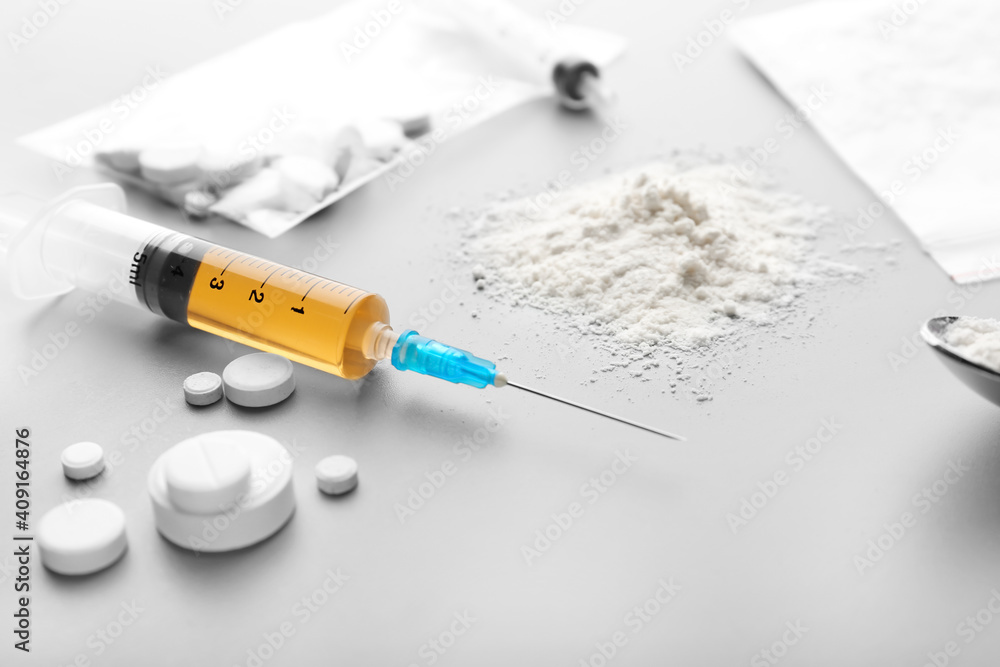 Syringe with drugs on light background