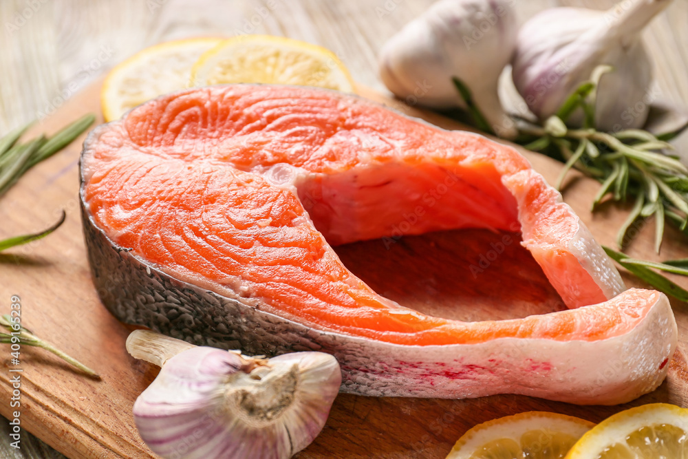 Raw salmon steak with garlic and lemon on wooden background