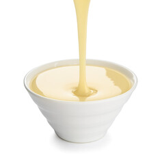 sweet condensed milk pouring into bowl on white background