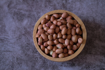 Wall Mural - Raw Groundnuts in the wooden bowl on cement background. Top view. 