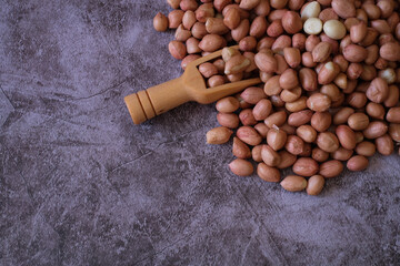 Wall Mural - Raw Groundnuts on cement background with wooden scoop. Top view. copy space for text.