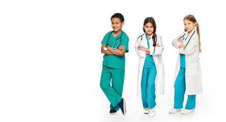 Group of positive multiethnic kids wearing medical uniforms, full-length. Concept of future doctors occupation