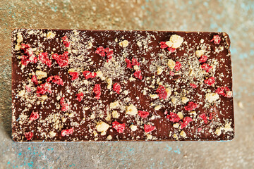 Wall Mural - Chocolate bar with nuts and berries on concrete background