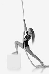 Wall Mural - beautiful ballerina in pointe shoes is posing with rope on white studio background. Black and white photo.