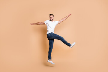 Poster - Full length body size view of attractive funky cheerful guy jumping having fun dancing isolated over beige pastel color background