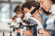 © Rido - High school girl looking through microscope at school