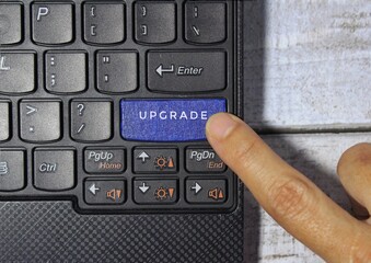 Wall Mural - finger pressing a blue key labeled upgrade with symbol on a computer keyboard concept