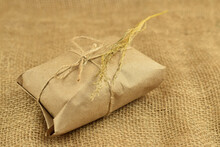 Simple Eco Friendly Gift Box Package Wrap With Brown Paper. Burlap Background. Delivery Of Ecological Products, Eco-friendly Packaging, Craft. Green Present Concept, Copy Space.
