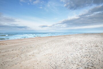 Wall Mural - Panoramic view of the Baltic sea from a sandy shore (sand dunes). Dramatic sky with glowing clouds, waves and water splashes. Idyllic seascape. Warm winter weather, climate change, nature. Denmark