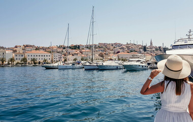 Rear view of female looking at beautiful seaside town. Mali Losinj, Croatia.