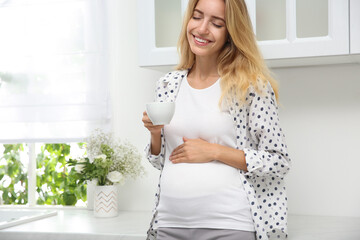 Poster - Beautiful pregnant woman drinking tea in kitchen