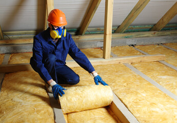 Wall Mural - Worker in protective respirator insulating glass wool insulation