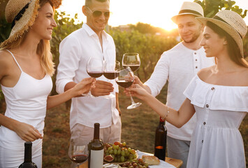 Wall Mural - Friends clinking glasses of red wine in vineyard