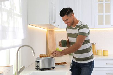 Canvas Print - Man using modern toaster at kitchen counter