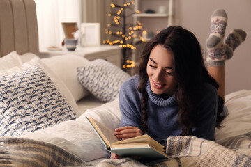 Poster - Young woman reading book at home. Winter atmosphere