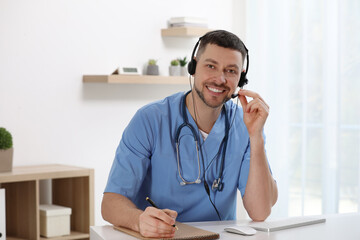 Wall Mural - Doctor with headset sitting at desk in clinic. Health service hotline