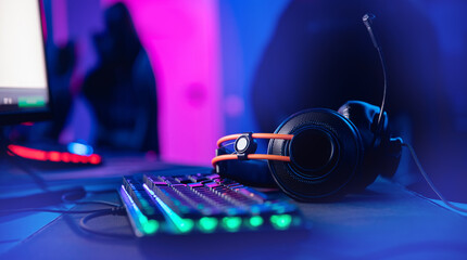 Wall Mural - Professional headphones with microphone for video games and cyber sports gaming monitor in neon color blur background