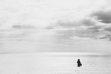 Sea and sky. People playing in the sea alone are lonely. Black and white photo.