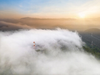 Wall Mural - Aerial view, Beautiful Panorama landscape sunrise over peak Mountain with mist and warm light sunrise at signal repeater station pole,  Communication technology concept. Mae Moh Lampang, Thailand