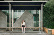© Cavan Images - Young girl sitting alone on a wooden seat at a bus stop