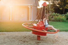 Young Girl Sitting On Playground Equipment At The Park