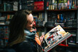 © marozzau - A beautiful woman in a book store holds an open comic book in the ruffs (the book is blurred).