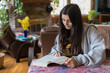 © Cavan Images - Mixed-race Teen girl with long hair reads book in comfortable interior