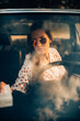 © Cavan Images - Young hipster woman looking to the window car.